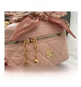 Detail of pink quilted leather cosmetic bag with golden floral logo and silk scarf