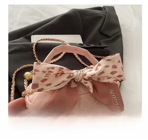 Detail of pink quilted mini bag with leopard silk scarf handle on a grey blazer