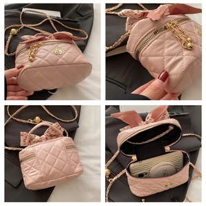 Detail view of pink quilted mini bucket bag with camellia metal clasp and silk scarf