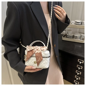 Detail of white quilted mini bucket bag with gold flower charm and leopard silk scarf