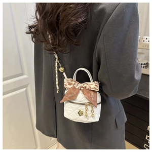 Detail of white quilted mini bag with gold floral charm and leopard print silk scarf