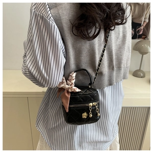 Detail of mini black quilted crossbody bag with silk scarf handle and golden chain