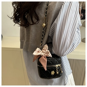 Detail of a quilted mini bag with gold chain strap and camellia flower ornament