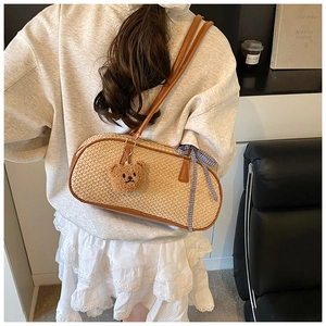 Detail view of woven straw shoulder bag with leather trim and plush bear charm