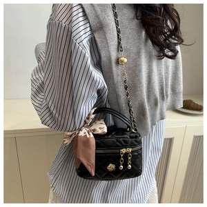 Close-up of black quilted mini bucket bag with gold flower logo and floral silk scarf