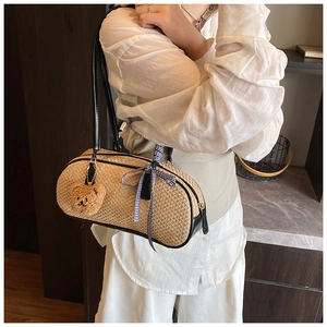 Detail showing natural straw weave, black leather trim, and cute plush bear charm