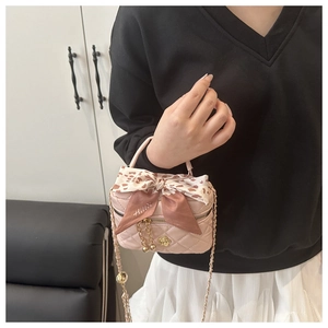Detail of pink quilted mini bag with golden flower charm and floral silk scarf handle
