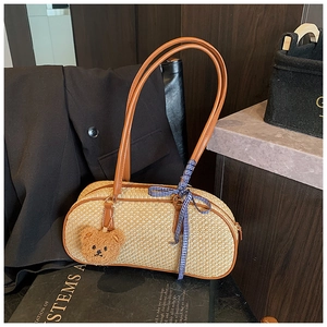 Close-up of woven straw shoulder bag with leather strap and cute bear charm pendant