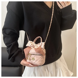 Pink quilted crossbody bag detail with leopard bow and golden flower charm
