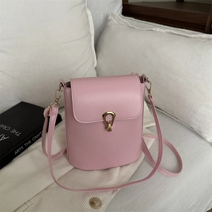 Pink leather mini bucket bag with gold ring buckle and shoulder strap in a cozy home setting