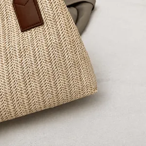 Detail shot of the woven herringbone texture and brown leather stitching on the shoulder bag