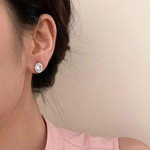 Elegant oval cubic zirconia stud earrings with halo setting worn by a female model