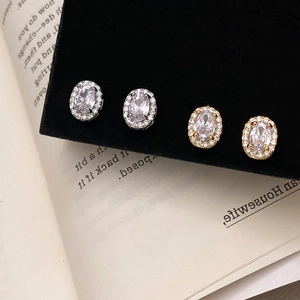 Elegant gold and silver halo stud earrings with oval cubic zirconia on black velvet background