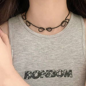 Detail of beaded black choker necklace with three metallic centered bows on a model