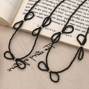 Handmade black faceted bead necklace with elegant bow design on vintage book background