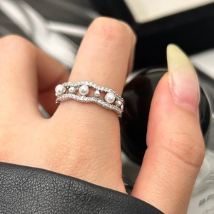Macro detail of a double-layered wavy silver ring with pearls and pavé zircons