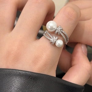Détail d'une bague ouverte en argent avec perles blanches et zircons pavés croisés