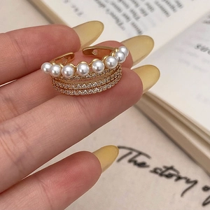 Détail d'une bague dorée multicouche avec sept perles blanches et accents de zircon