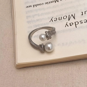 Vue détaillée d'une bague ajustable en perles et zircons posée sur un livre ancien