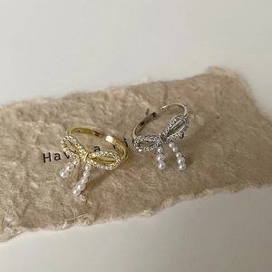 Elegant bow-shaped open rings with micro-set zircons and dangling pearls in gold and silver