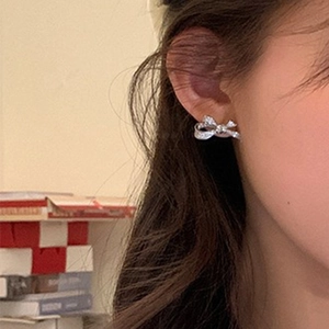 Close-up of sparkling zircon bow earrings in silver finish worn by a model