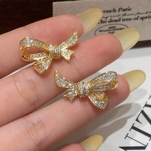 Detailed shot of gold bow earrings featuring micro-pave cubic zirconia on magazine background
