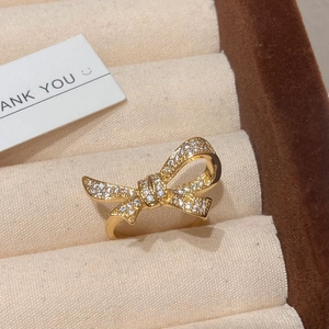 Detailed view of a golden bow ring with cubic zirconia on a beige velvet jewelry box