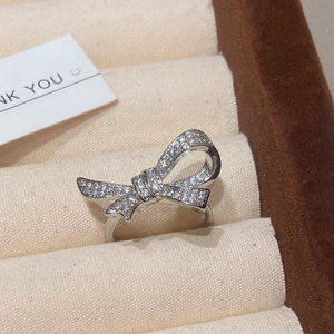 Detailed view of shimmering zircon bow ring displayed on a soft velvet jewelry holder