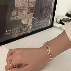 Close-up of a silver twisted double-layer bangle and a pearl ring on a model's hand