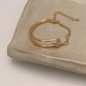 Close-up of golden double-layer interwoven bracelet with adjustable chain on a tray