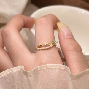 Macro shot of a gold butterfly ring featuring inlaid crystals and elegant small pearls