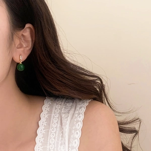 Detailed close-up of French vintage green chalcedony tassel earrings worn on ear