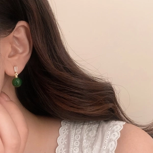 Close-up of vintage emerald green chalcedony drop earring with zircon on model