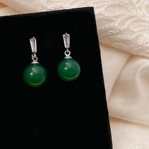 Macro detail of vintage green agate drop earrings with cubic zirconia on black velvet