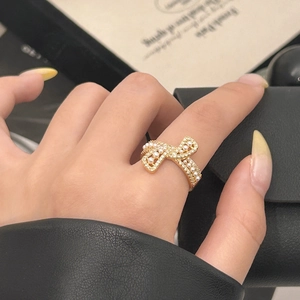 Macro detail of golden bow ring featuring white faux pearls and sparkling zircons