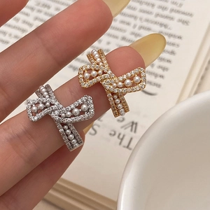 Elegant bow knot ring with pearls and zircons shown in a hand-worn pose for a vintage look