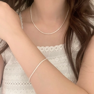 Ensemble collier et bracelet minimaliste scintillant porté sur un mannequin en dentelle