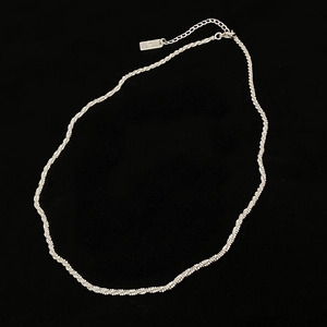 Gros plan d'un collier tressé argenté avec chaîne réglable et détail de pendentif rectangulaire