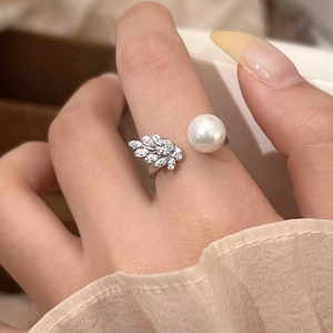 Macro detail of adjustable silver ring with zircon leaf and white pearl on finger