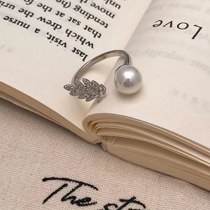 Macro detail of leaf-shaped zircon ring with white pearl on vintage book pages