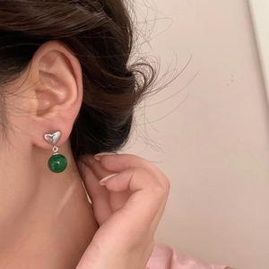 Elegant heart-shaped silver earrings with round green chalcedony beads on female model