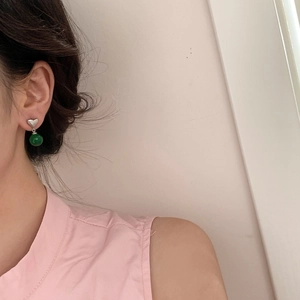 Close-up of heart-shaped silver earrings with elegant dark green chalcedony stone drop