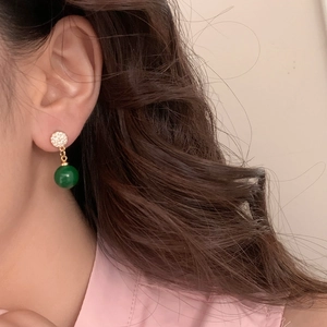 Élégantes boucles d'oreilles en zircon vert émeraude plaquées or sur un modèle