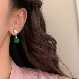 Gros plan de boucles d'oreilles pendantes avec pavé de cristaux et perles émeraude