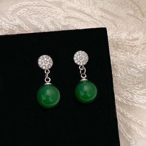Détail de boucles d'oreilles perles vert émeraude avec micro-pavé de cristaux de zircon