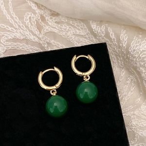 Vue détaillée de boucles d'oreilles créoles dorées avec pendentif en calcédoine verte