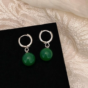 Détail de créoles en argent avec sphères en calcédoine vert foncé sur velours noir