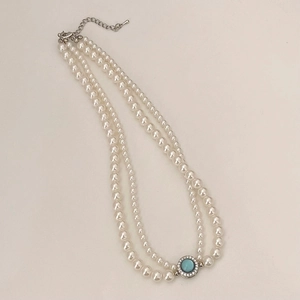 Détail d'un collier de perles à deux rangs avec pendentif gemme bleue et fermoir argent