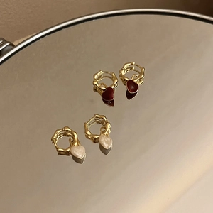 Détail de boucles d'oreilles en forme de cœur bordeaux et blanc sur un miroir rétro
