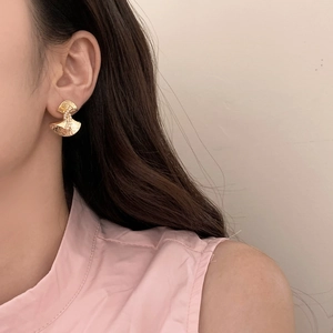 Close-up of elegant gold ginkgo leaf earrings with pearl detail on a model